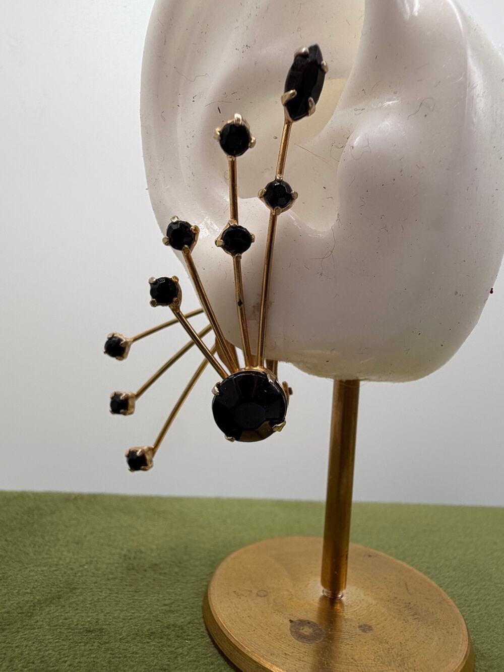 atomic-inspired clip on black glass surrounded by smaller bead-tipped sprays